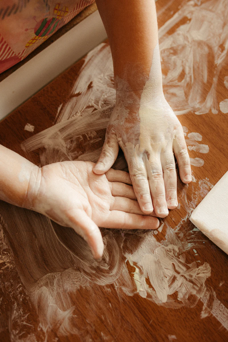 Two small hands pressing into soft clay