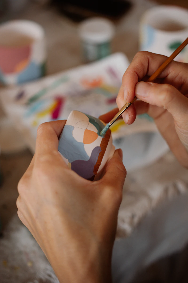 Close-up of hands painting soft shapes onto a figure