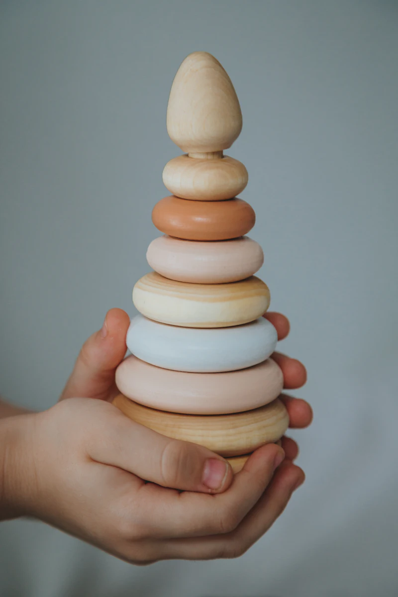 A hand holding a stack of pastel wooden rings