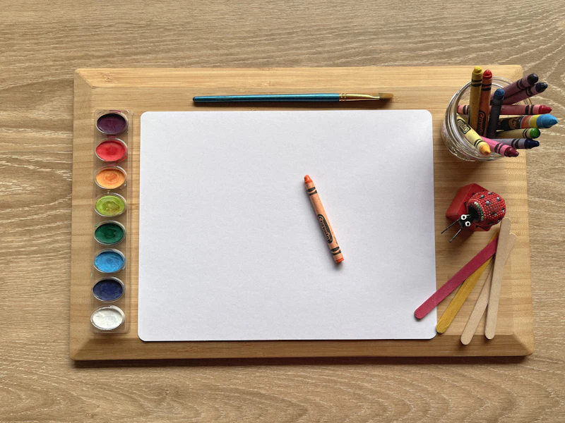 A wooden tray with paper, paints and pencils